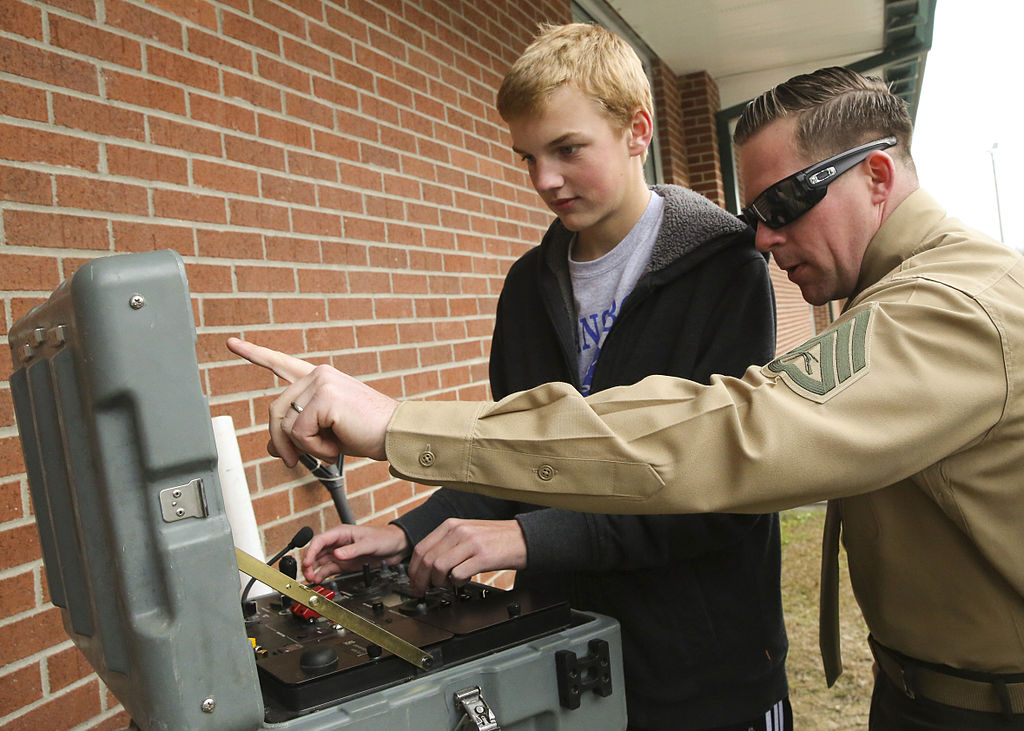 U.S. Marine Corps Staff Sgt. Keith J. Losordo shows a high-school student how to remotely operate the Mk2 Talon robot.