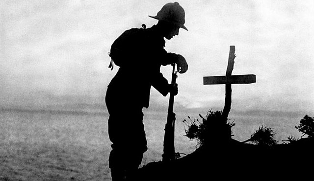 A WWI soldier visits the grave of a fallen comrade.