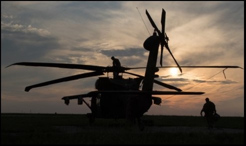 A silhouette of a helicopter at sunset Description automatically generated